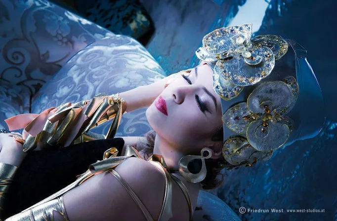 Model mit Schmuck-Kopfputz liegend in blauem Licht, Augen geschlossen