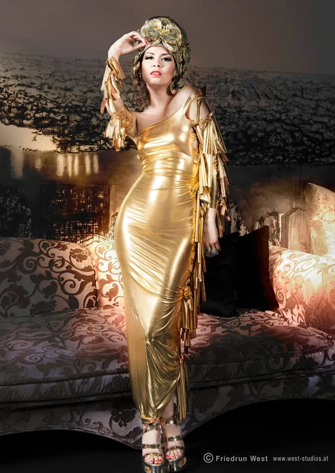 Model im goldenen Kleid mit Kopfschmuck in einem dunklen Salon