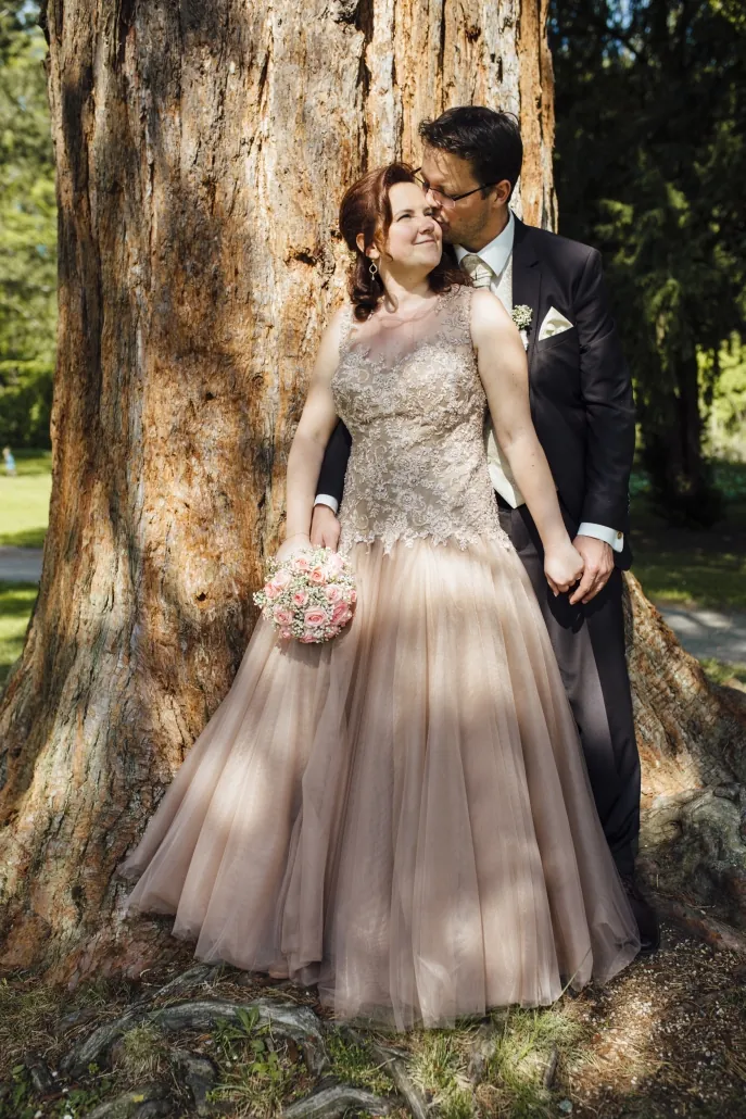 Brautpaar an einem Baumstamm, Braut im roséfarbenen Tüllkleid