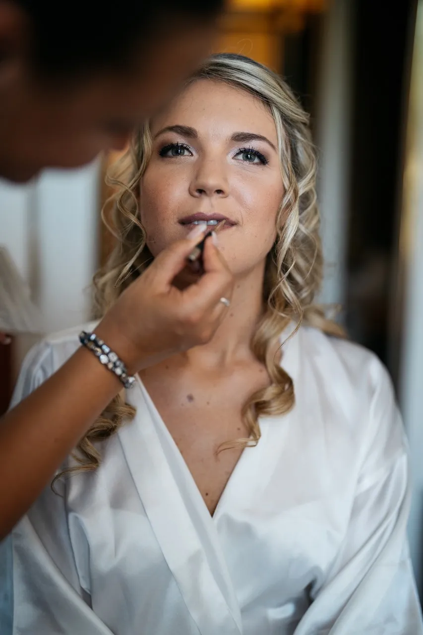 Lippenstift wird bei einer Braut im weißen Morgenmantel aufgetragen