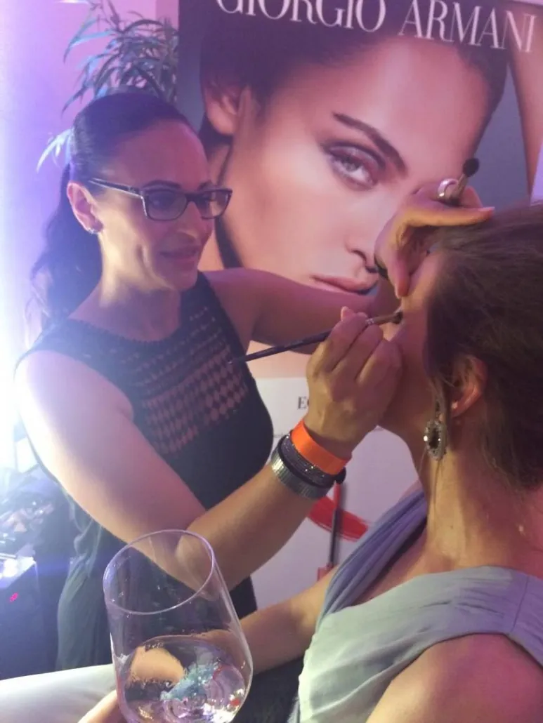 Make-up-Artist schminkt eine Frau vor einem großen Beauty-Plakat